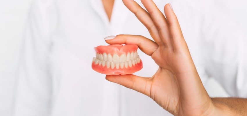 Une prothèse dentaire dans la main d'un dentiste